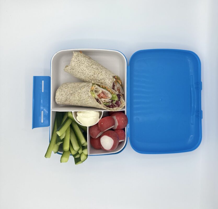 NjaNja gezonde lunchbox op school geleverd: volkoren wrap, radijs, komkommer, verse kaas