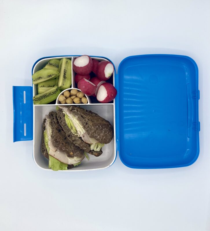NjaNja gezonde lunchbox op school geleverd: broodje caesar, kiwi, radijs, kikkererwten