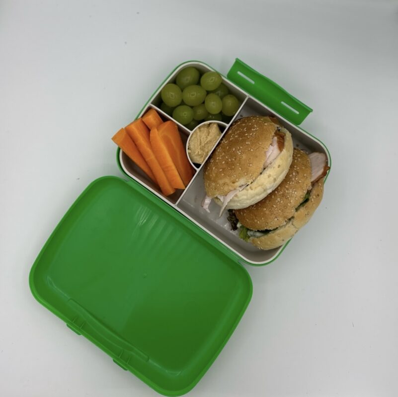 NjaNja gezonde lunchbox op school geleverd: bruine pistolet caesar, druiven, wortel, hummus