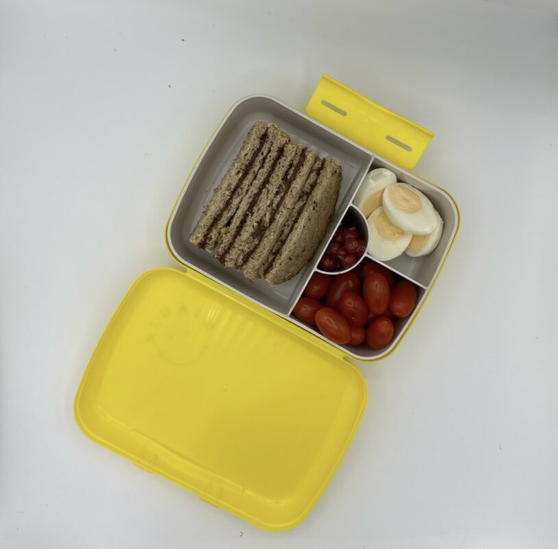 NjaNja gezonde lunchbox op school geleverd: boterham notenpasta, gekookt ei, kerstomaten, cranberry's