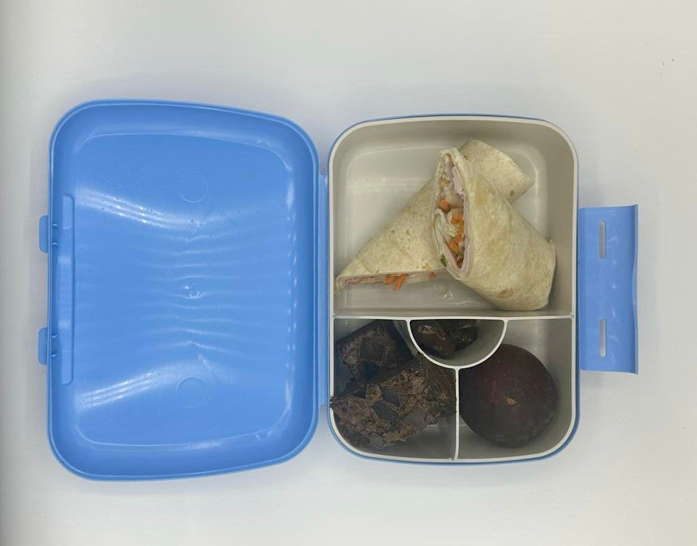 NjaNja gezonde lunchbox op school geleverd: Brooddoos-Njanja- wrap met kalkoenfilet en groenten-bessencake-pruim-dadel
