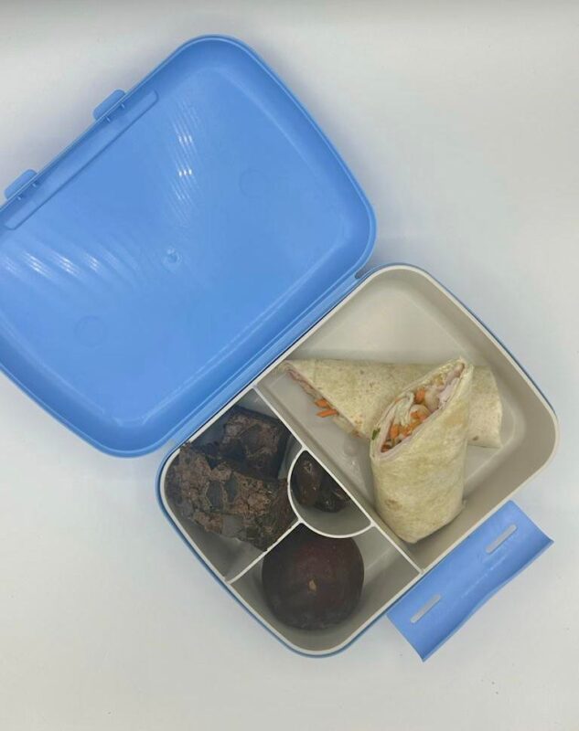 NjaNja gezonde lunchbox op school geleverd: Brooddoos-Njanja- wrap met kalkoenfilet en groenten-bessencake-pruim-dadel