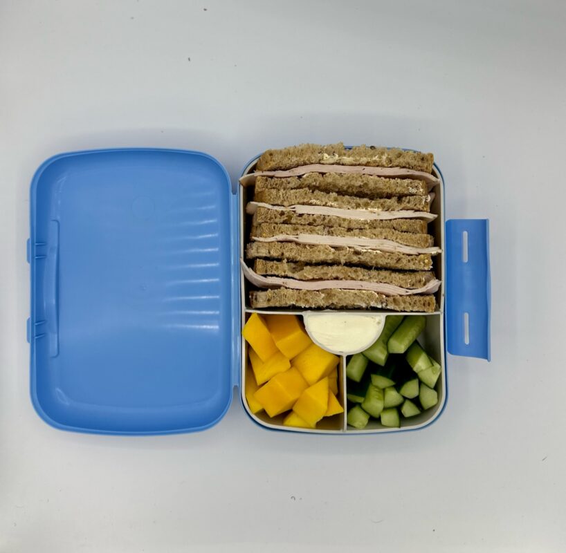 NjaNja gezonde lunchbox op school geleverd: boterham kipfilet, komkommer, mango, verse kaas