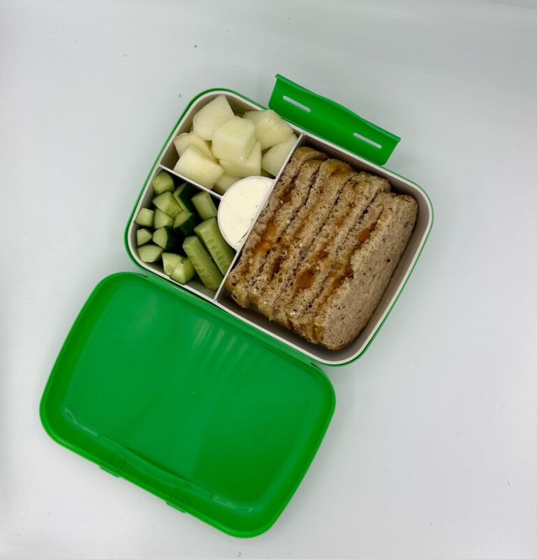 NjaNja gezonde lunchbox op school geleverd: boterham huisgemaakte aardbeiconfituur, komkommer, meloen, verse kaas