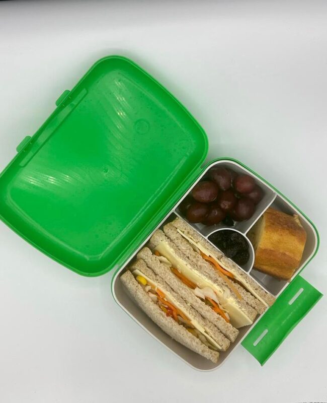 NjaNja gezonde lunchbox op school geleverd: Njanja-brooddoos-boterham groenten en kaas-yoghurtcake-druiven-rozijnen-schuin