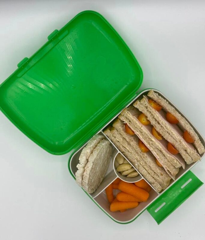 NjaNja gezonde lunchbox op school geleverd: Njanja-brooddoos-boterham kalkoenfilet en tomaat-wortel-rijstcrackers-amandelen-schuin