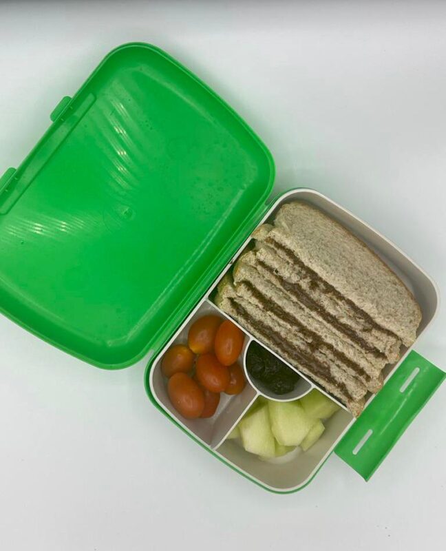 NjaNja gezonde lunchbox op school geleverd: Njanja-brooddoos-boterham notenpasta-kerstomaten-meloen-rozijnen-schuin