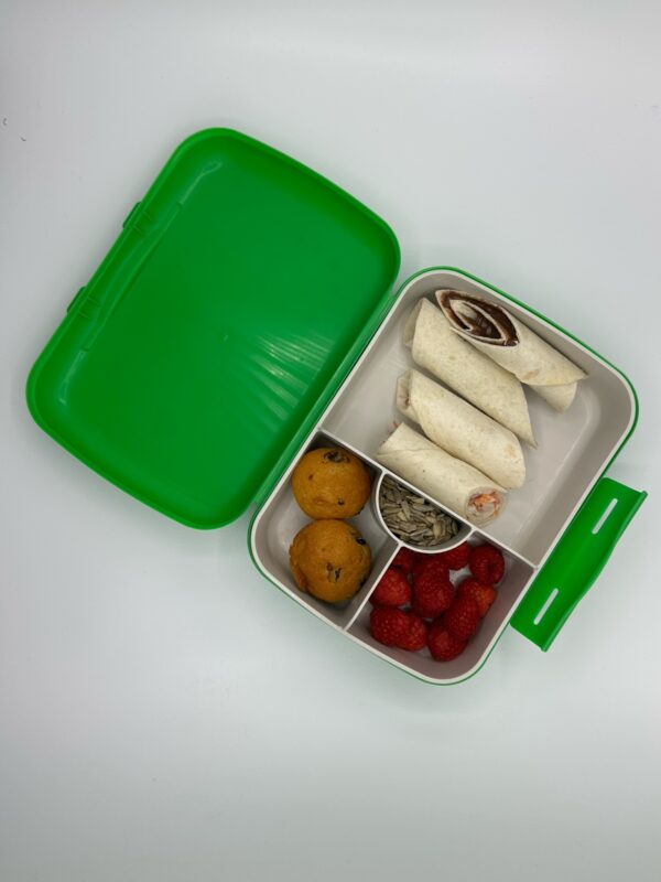 Njanja-brooddoos-wrap kip en groentjes en yoghurtdressing + wrapschijfjes notenpasta-mini muffin-rood fruit-zonnebloempitten-schuin